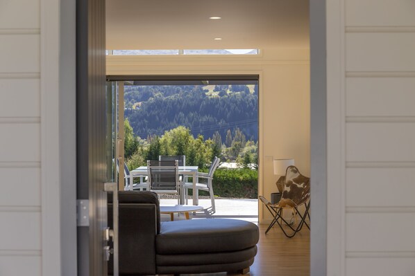 Un intérieur moderne offrant une vue sur un paysage montagneux grâce à une grande porte vitrée.