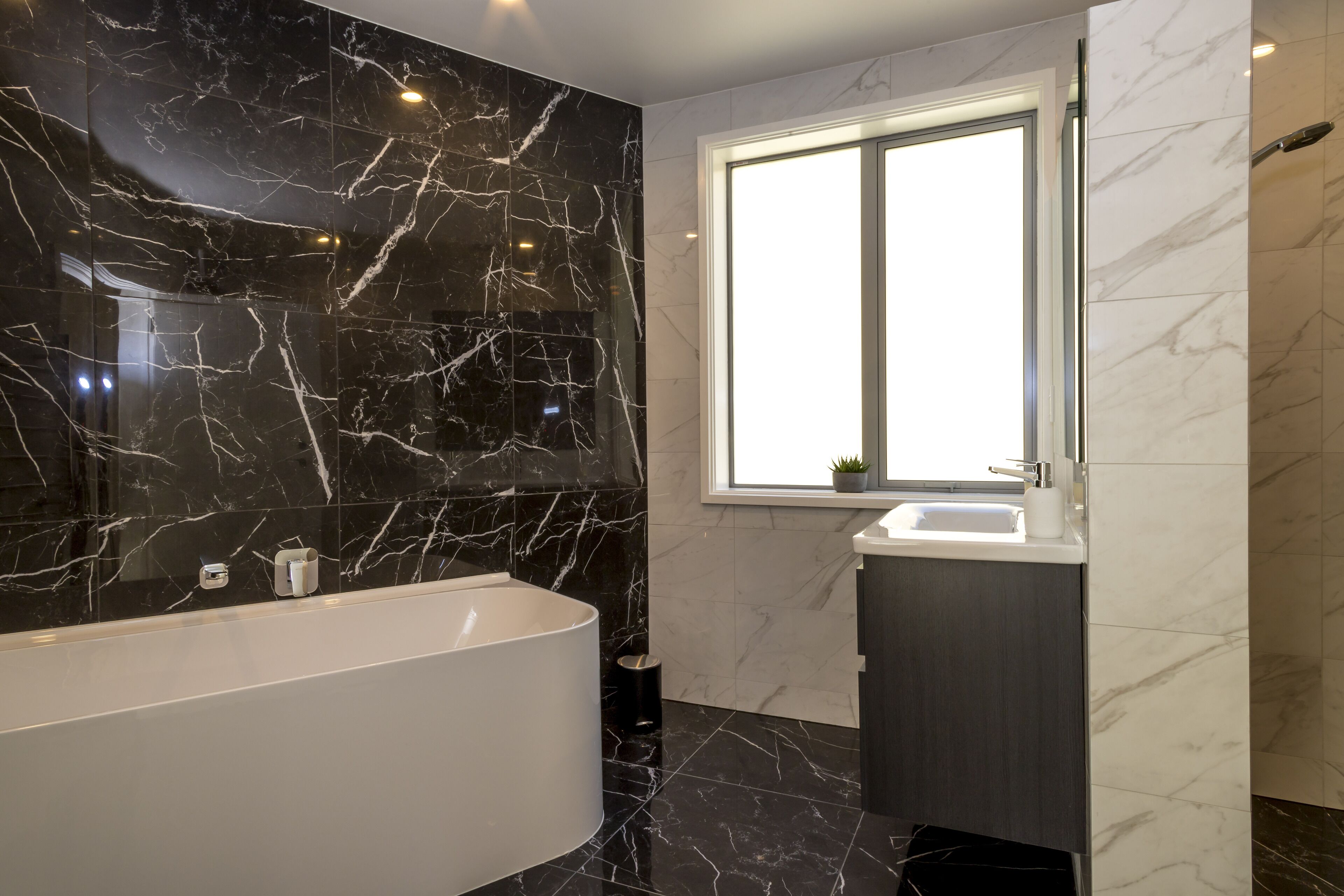 A modern bathroom with a freestanding bathtub, a window, and a sink.