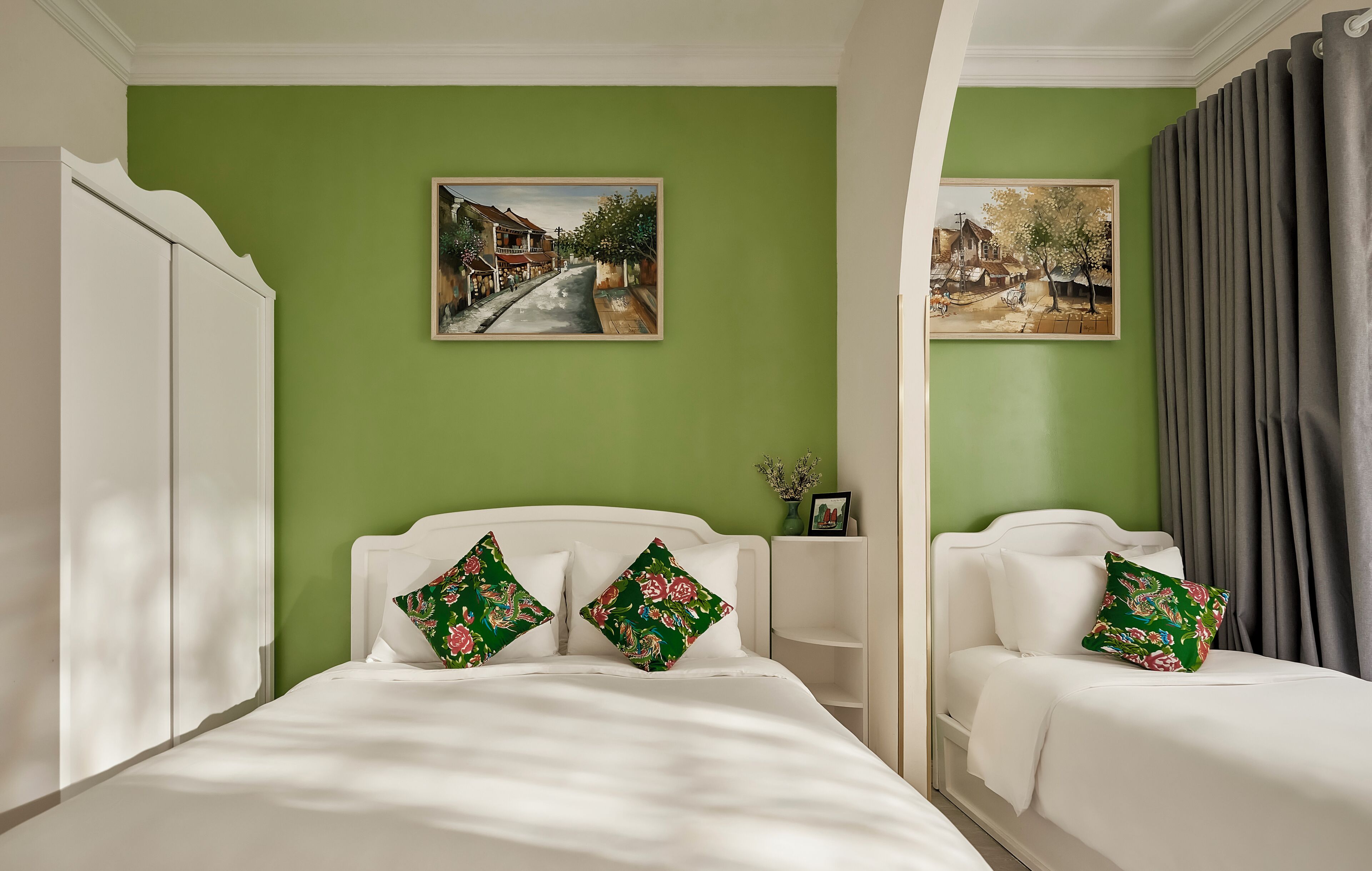 Ein Zimmer mit zwei Betten, grünen Wänden und zwei Bildern.