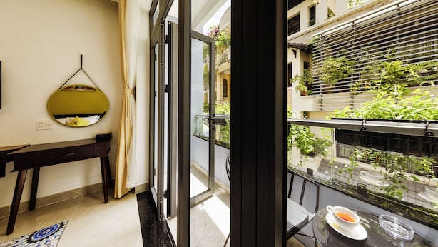 A modern room with a large window, a dining table with a cup and saucer, and a hanging light fixture. - Chez Mimosa Petite (Ho Chi Minh City)