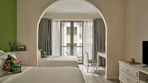 A hotel room with two beds, a desk, a TV, and a balcony with curtains. - Chez Mimosa Petite (Ho Chi Minh City)