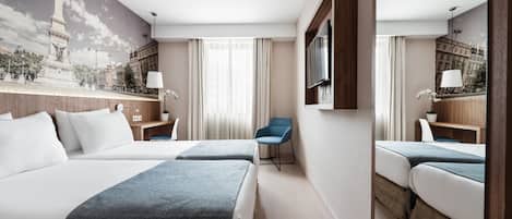 A hotel room with two beds, a TV, a desk, and a chair.
