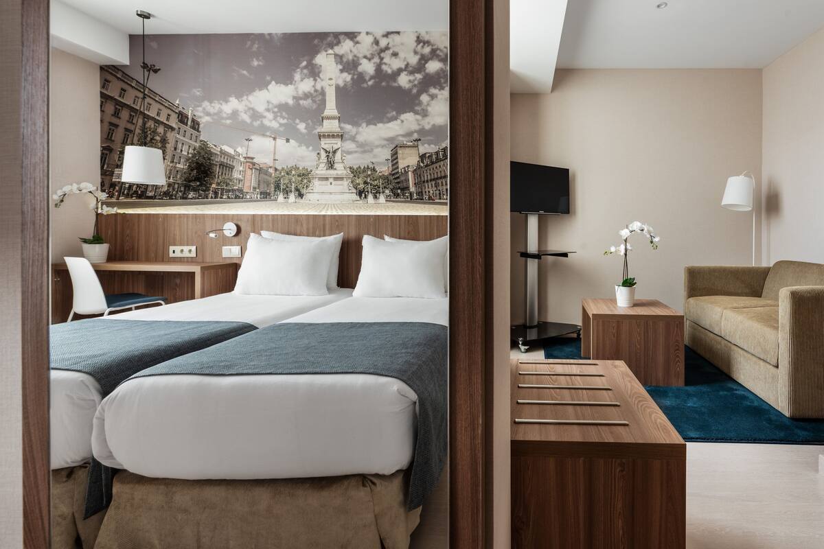 Una habitación de hotel con una cama, un escritorio, una silla, un televisor y un sofá.