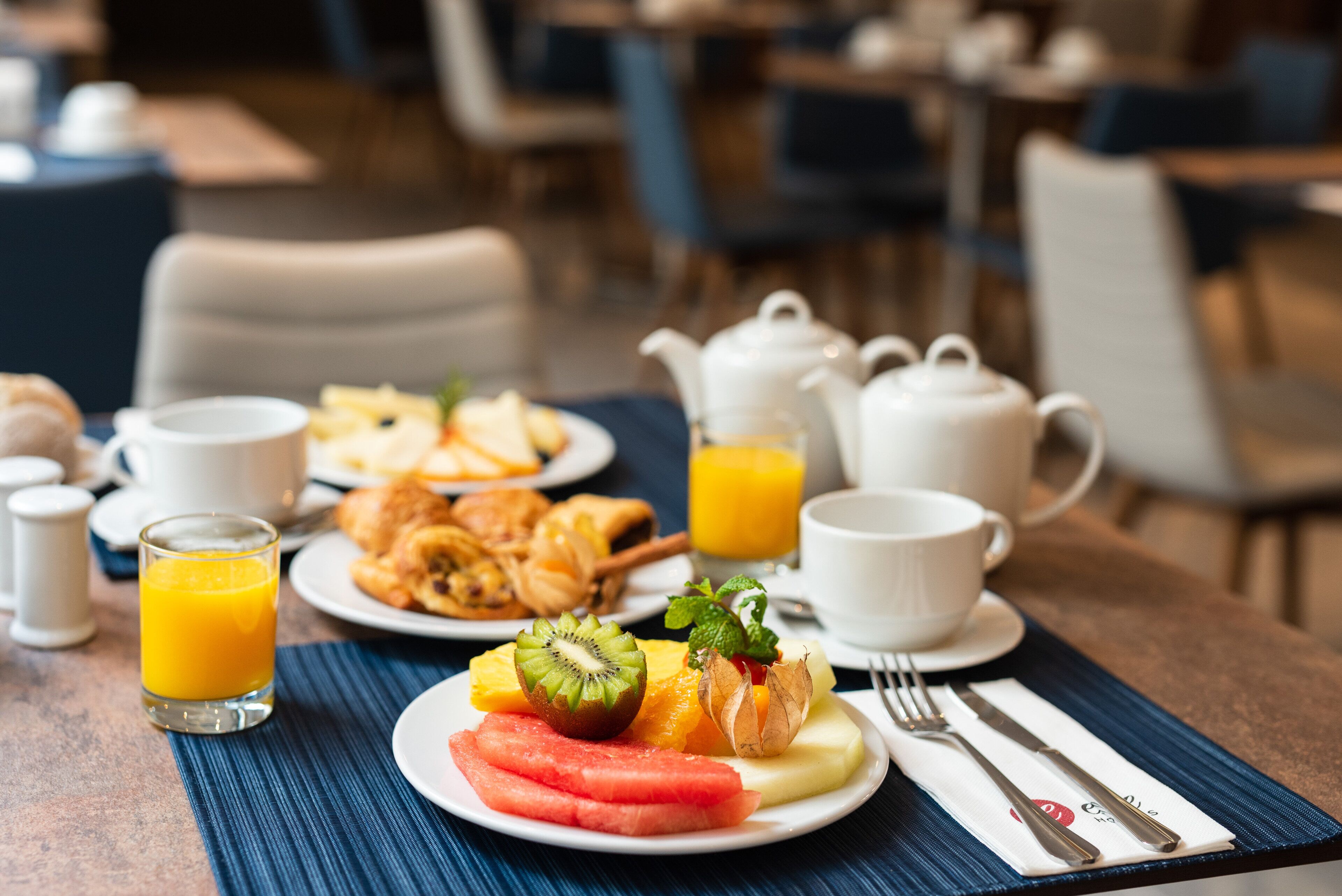 Ein Frühstückstisch mit Fruchtschalen, Croissants und einer Teekanne.