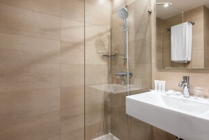 A modern bathroom with a glass-enclosed shower, a white sink, and a mirror above the sink.