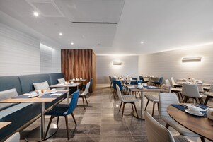Un comedor moderno con una combinación de cabinas y mesas, detalles de madera y un techo con estampado.