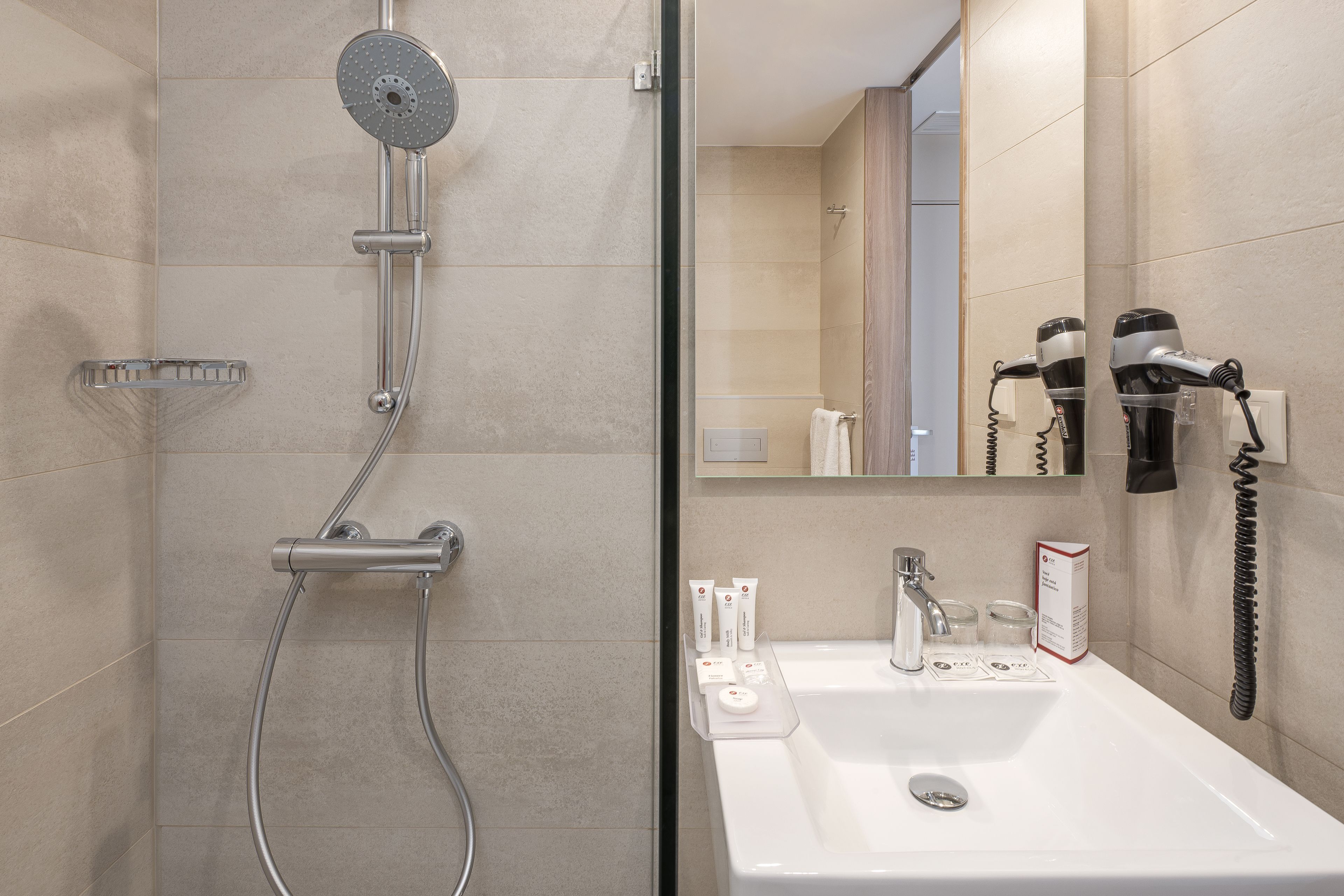 Een moderne badkamer met een douche, wastafel en haardroger.