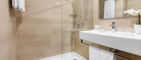 Un baño moderno con ducha de vidrio, un lavabo blanco y un espejo sobre el lavabo.