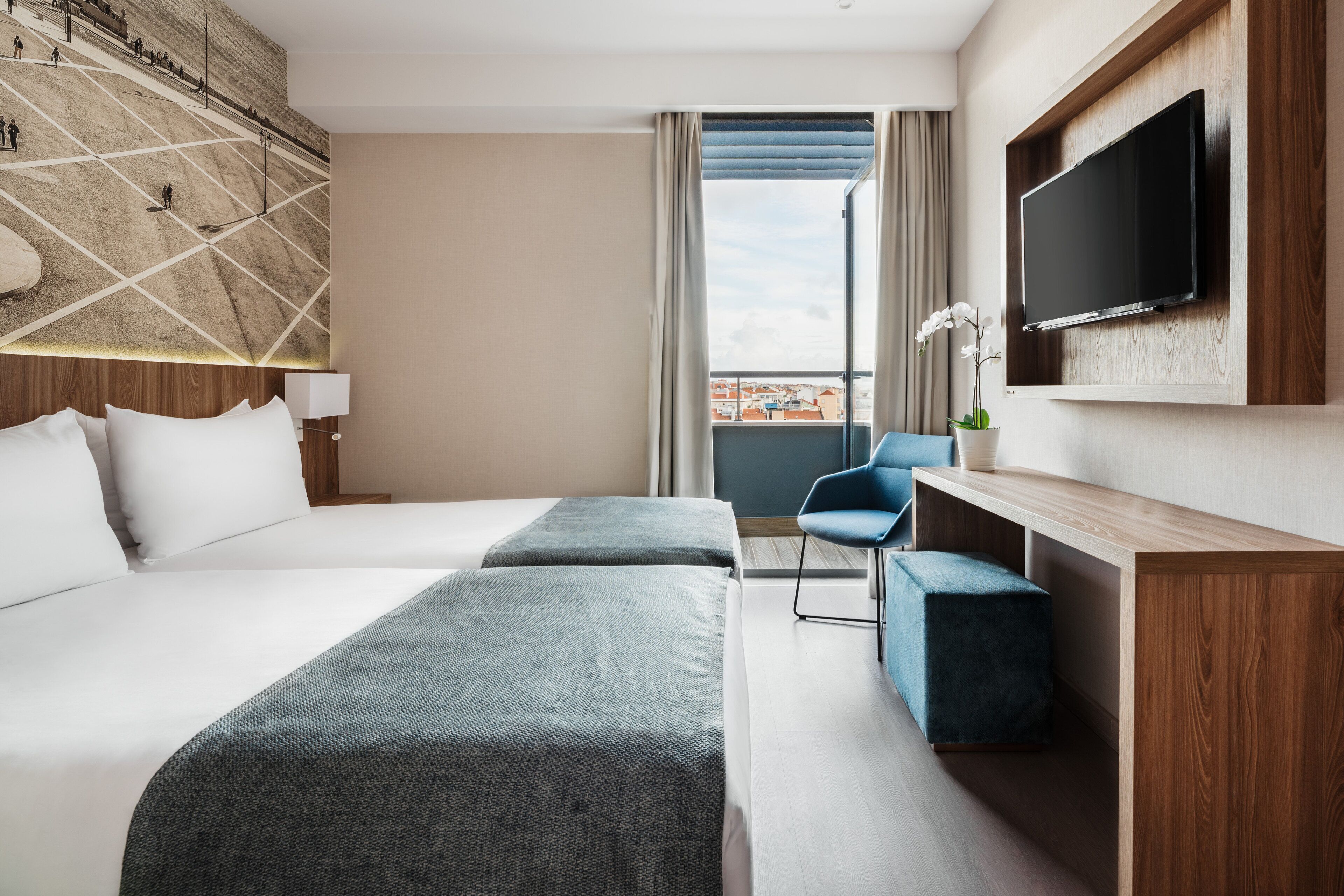 Een hotelkamer met een groot bed, een bureau, een stoel, een televisie en uitzicht op de stad.