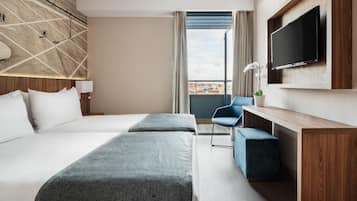 Een hotelkamer met een groot bed, een bureau, een stoel, een televisie en uitzicht op de stad.
