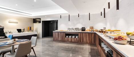 A modern kitchen with a central island, built-in appliances, and a dining area with chairs and a table.