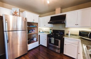 Kitchen features a refrigerator, range hood, oven, and microwave, along with white cabinetry and a countertop.