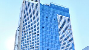 A high-rise building with a grid of windows and a prominent logo at the top. - Ramada Encore by Wyndham Busan Station (Busan)