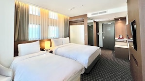 A hotel room with two beds, a desk, a chair, a TV, and a bathroom door. - Ramada Encore by Wyndham Busan Station (Busan)