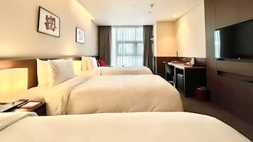 A hotel room with two beds, a desk, a TV, and a window with curtains.