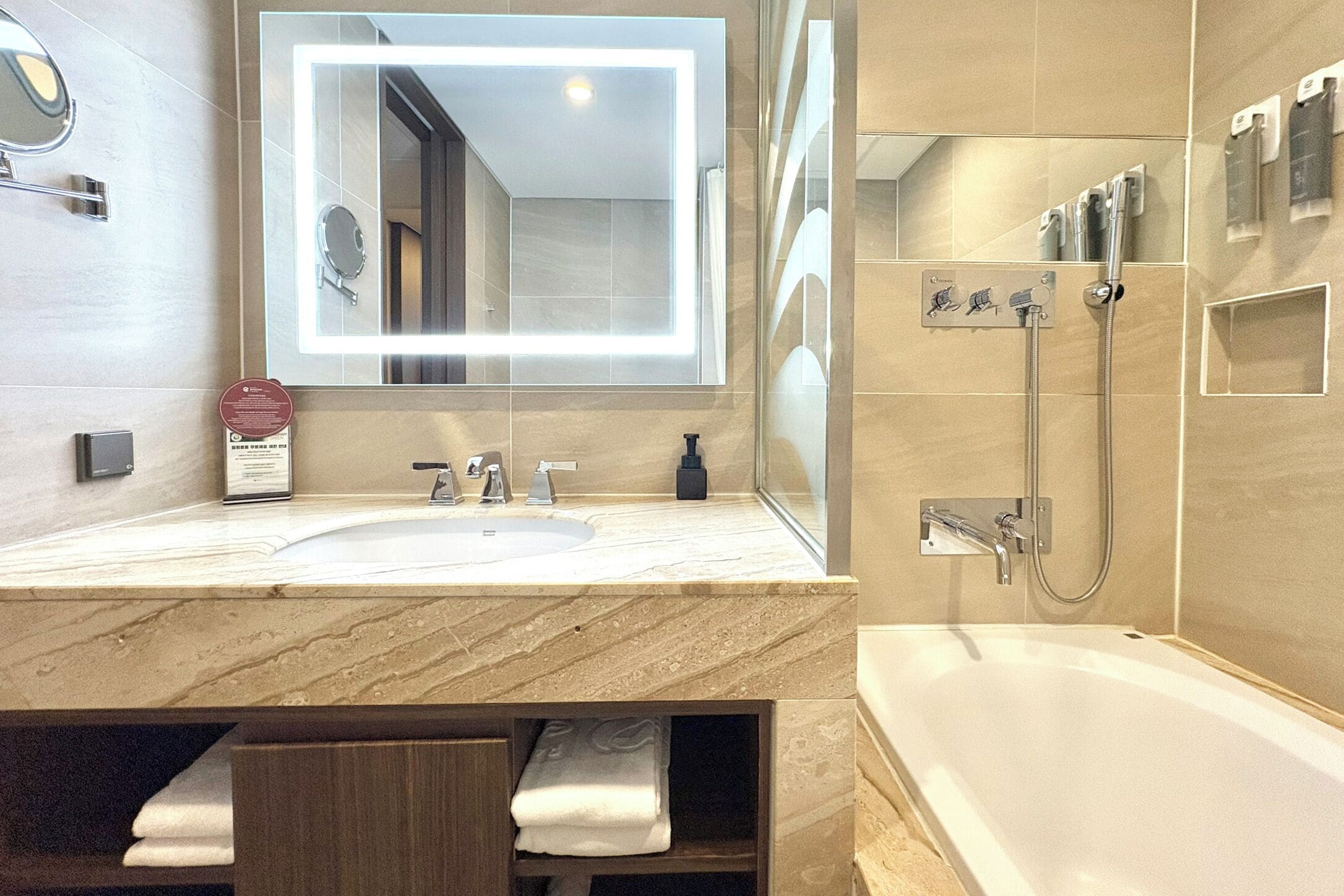 A modern bathroom with a large mirror, a sink, a shower, and a bathtub.