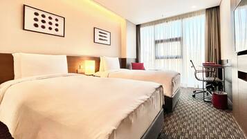 A hotel room with two beds, a desk, a chair, a TV, and a window with curtains.
