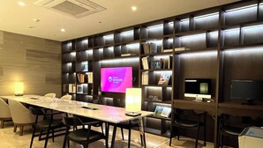 A modern conference room with a long table, chairs, a large screen, bookshelves, and a desk with a computer. - Ramada Encore by Wyndham Busan Station (Busan)