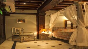 Un dormitorio con cama a dosel, una mesita de noche con lámpara, una silla y una pequeña mesa.