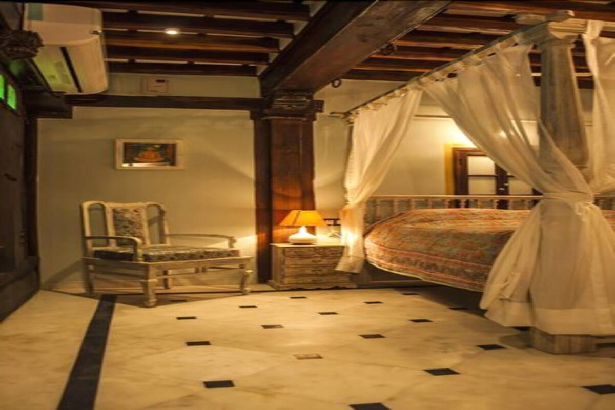 Une chambre à coucher avec un lit à baldaquin, une table de chevet avec une lampe, une chaise et une petite table.