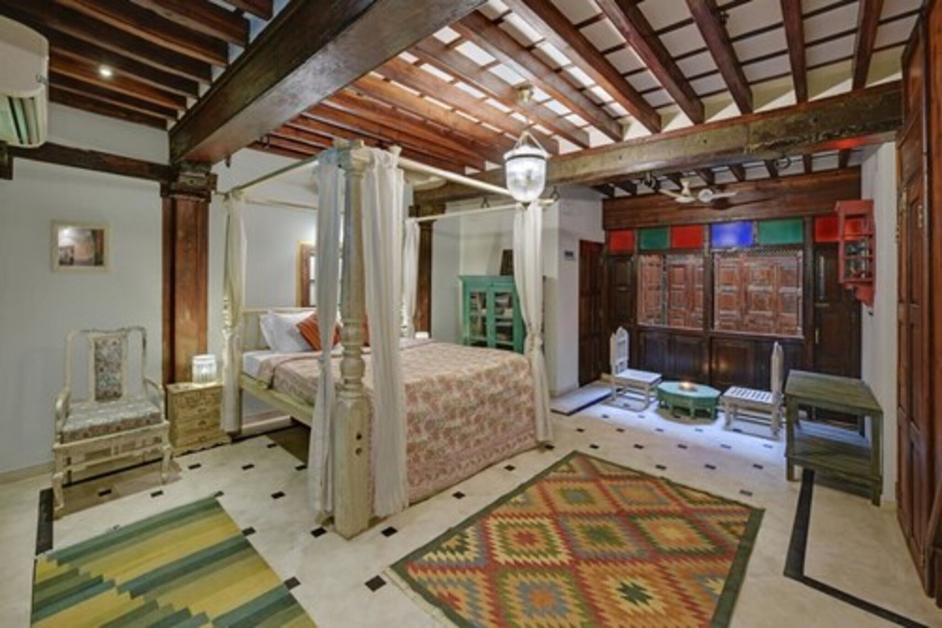 A traditional bedroom with a four-poster bed, a green cabinet, and a patterned rug.