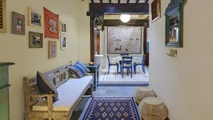 Una habitación acogedora con un banco de madera, un tapete estampado y un área de comedor con sillas y una mesa.