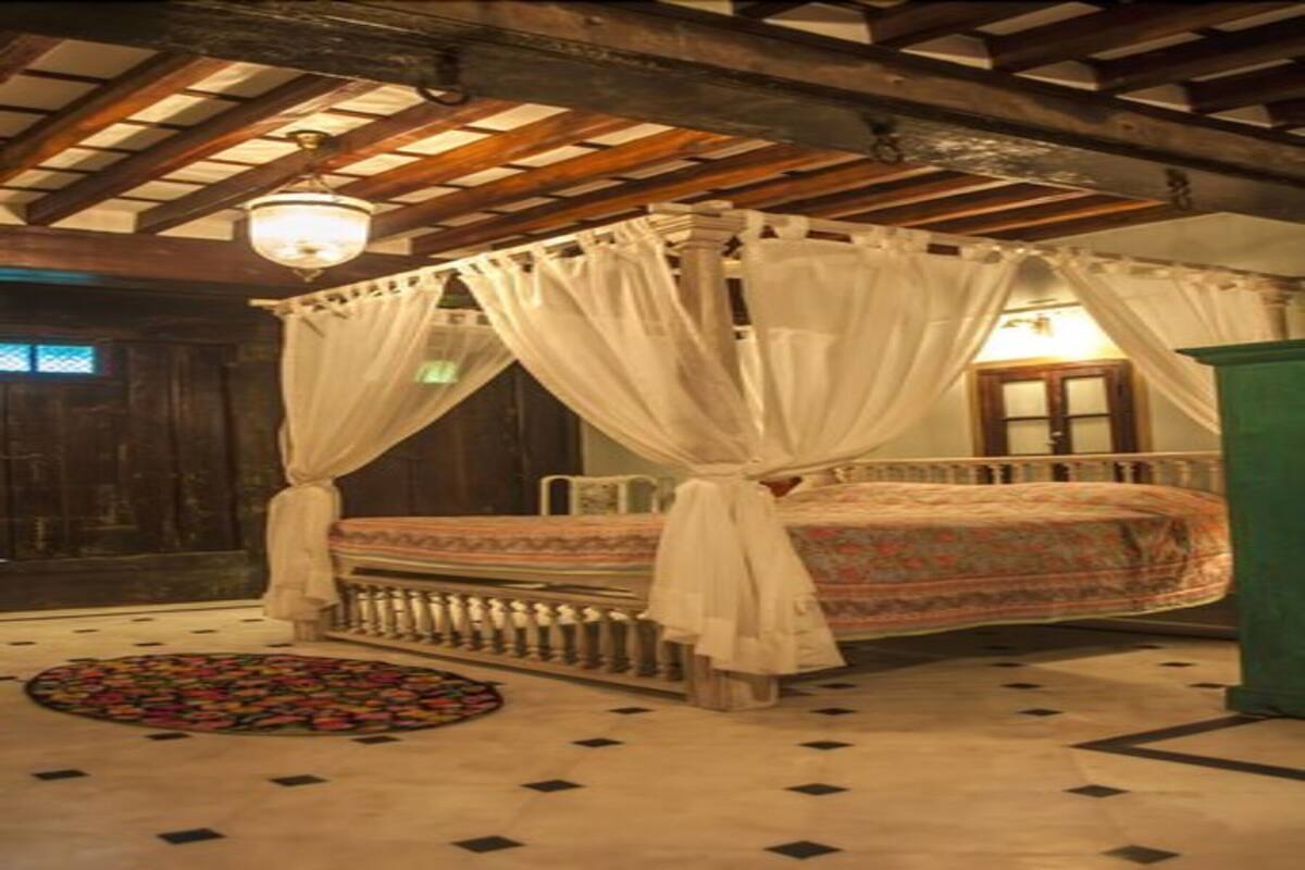 Une chambre avec un lit à baldaquin, une moquette ronde et un plafond en bois.
