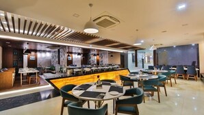 A modern restaurant with a central bar area, multiple dining tables, and a mix of seating arrangements. - The Royal Grand (Karur)