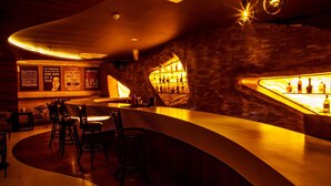 Un espace bar doté d’un comptoir incurvé, de tabourets et d’un mur en briques.