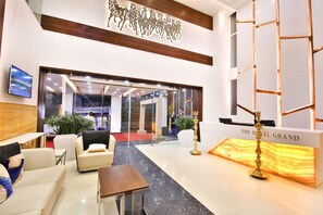 Un vestíbulo de hotel con mostrador de recepción, zona de estar y una pared decorativa con siluetas de caballos.