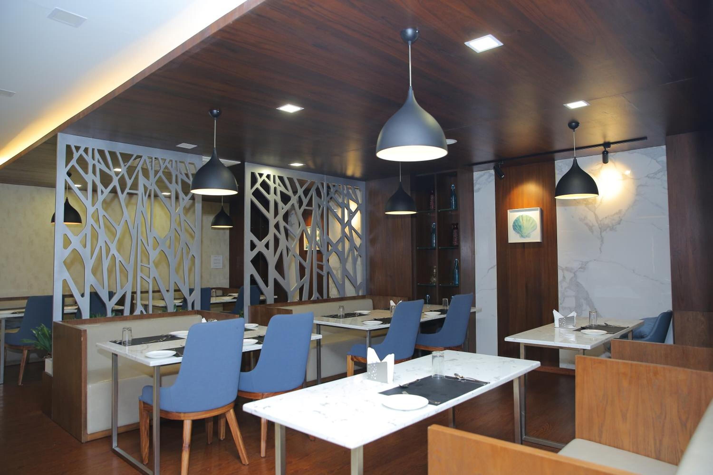 A modern restaurant with wooden ceiling, blue chairs, and black pendant lights.