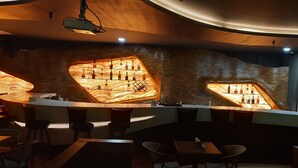 A bar area with a unique wooden design and shelves displaying bottles. - The Royal Grand (Karur)