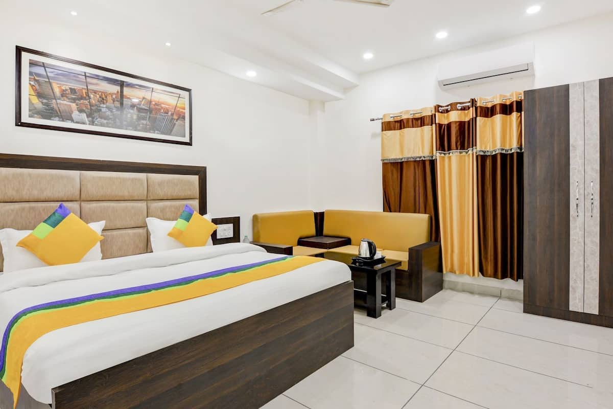 A hotel room with a bed, a nightstand, a chair, a wardrobe, and a painting on the wall.