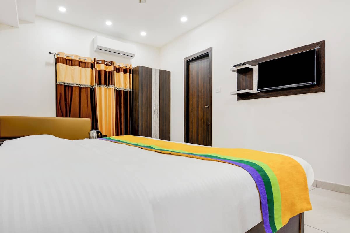 A hotel room with a bed, a chair, a wardrobe, and a television.