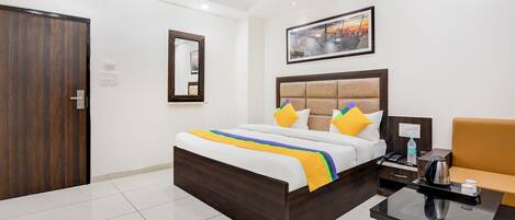 Una habitación de hotel con una cama de madera, una mesita de noche con una tetera y una silla.