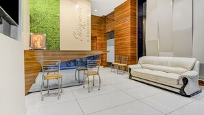 A modern reception area with a green wall, a wooden reception desk, and a white sofa. - Itsy Hotels K K Residency Staywell (Roorkee)