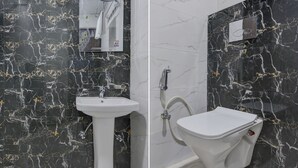 A bathroom with a black marble wall, a white sink, and a toilet. - Itsy Hotels K K Residency Staywell (Roorkee)
