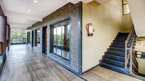 A spacious hallway with a wooden floor, large windows, and a staircase with a metal railing. - Treebo Garden Cottage & Lawn Mahabaleshwar (Mahabaleshwar)