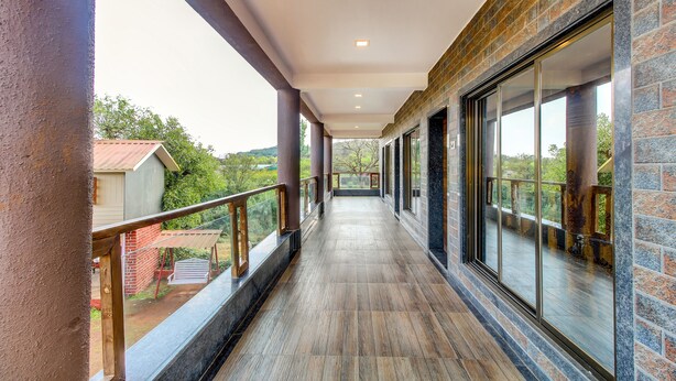 A corridor with a wooden floor, glass doors, and a view of greenery outside. - Treebo Garden Cottage & Lawn Mahabaleshwar (Mahabaleshwar)