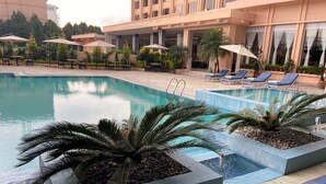 Zona de piscina de hotel con sillones reclinables, sombrillas y un letrero que dice 'The Everest Hotel'.
