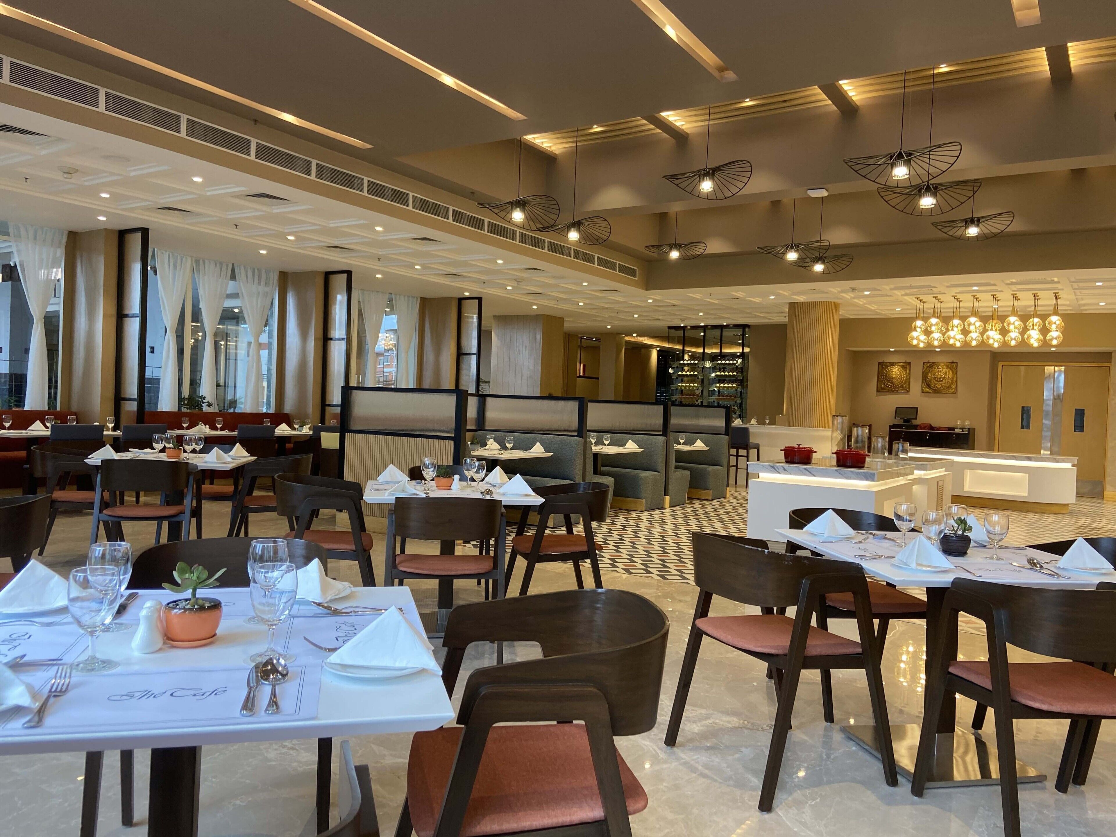 A spacious restaurant with multiple dining areas, modern lighting fixtures, and a clean, contemporary design.