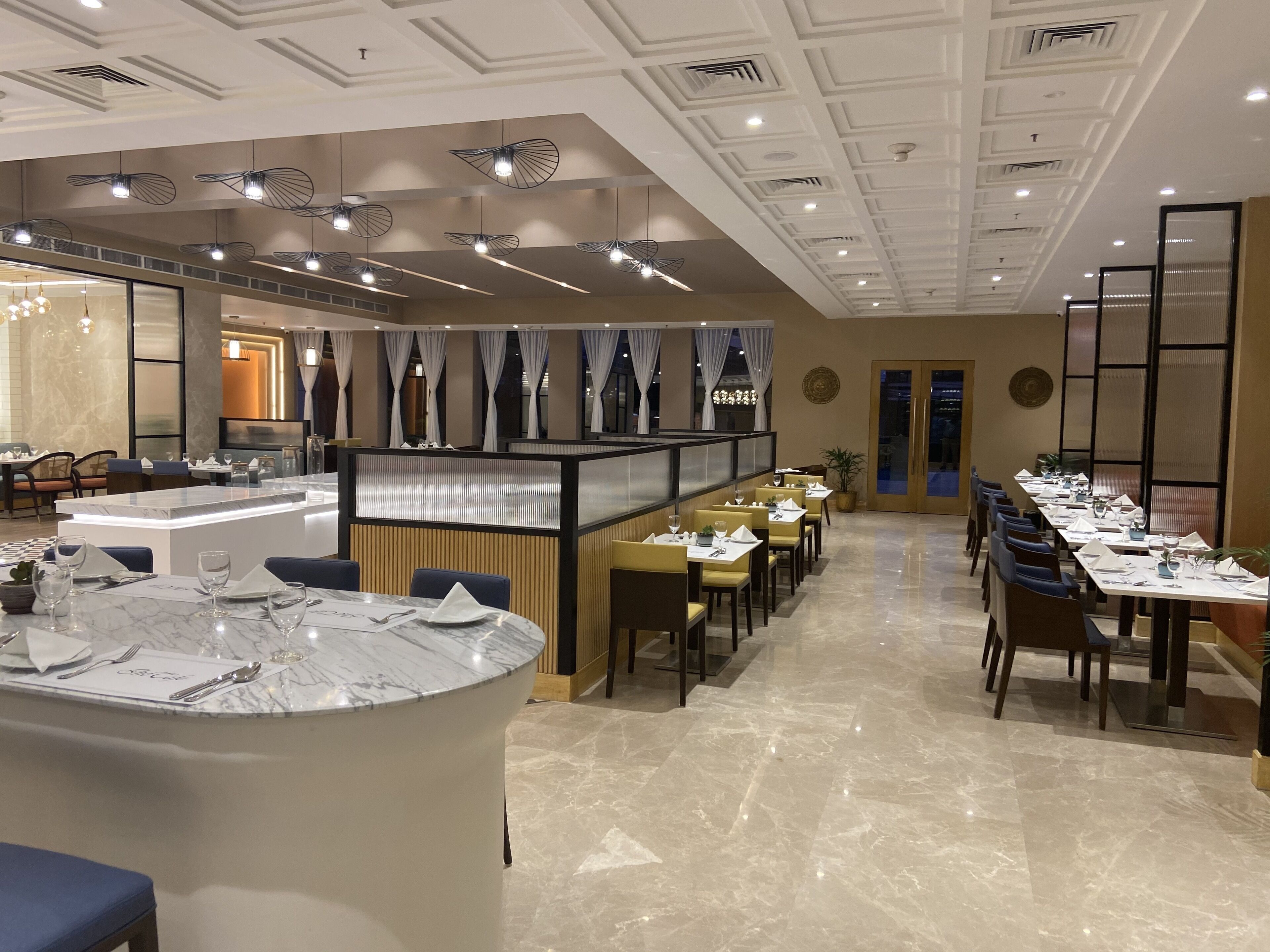 A modern restaurant with a long dining area, a bar area, and a separate seating section.
