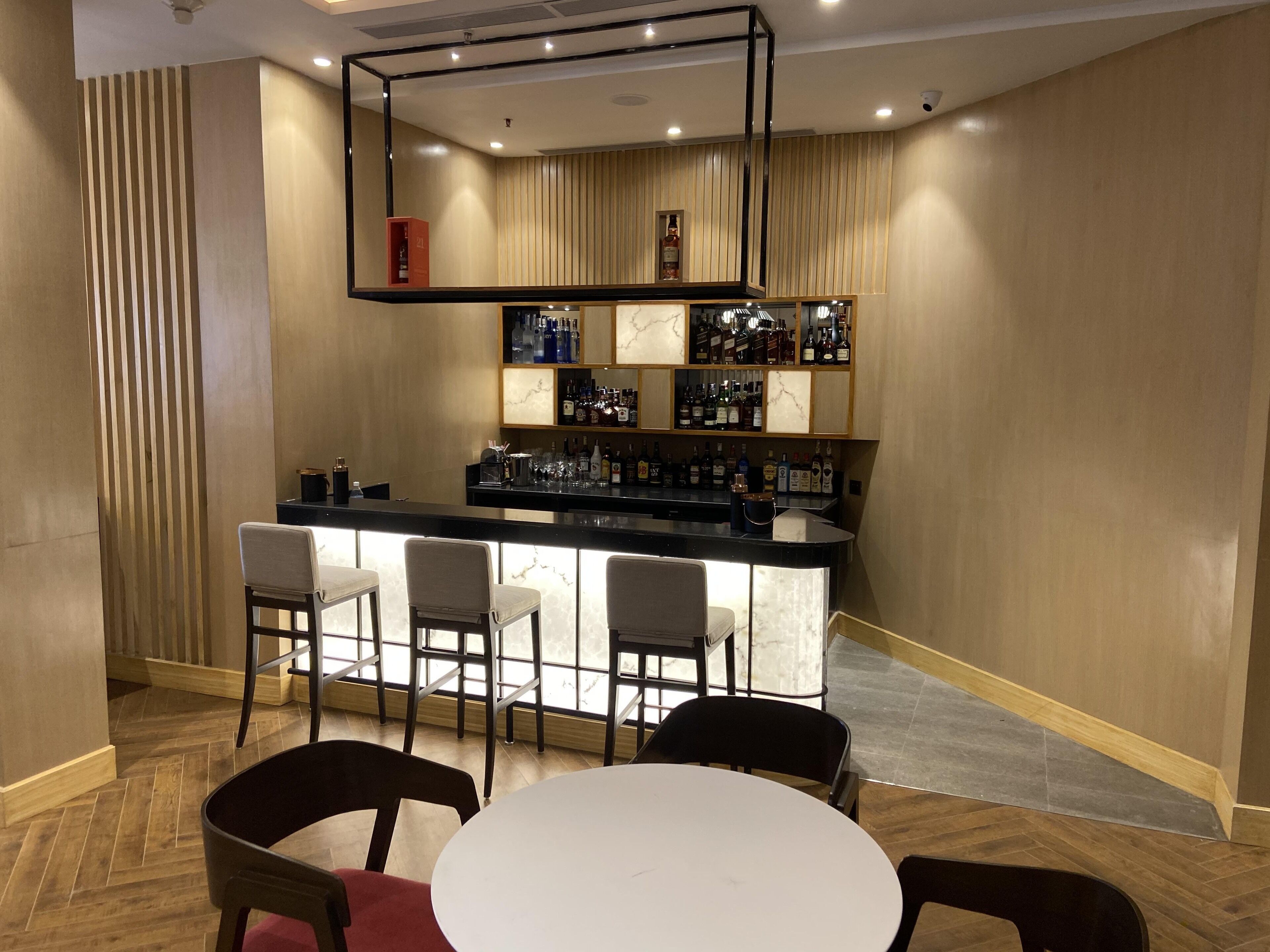 A bar area with a counter, bar stools, and a seating area with a round table and chairs.
