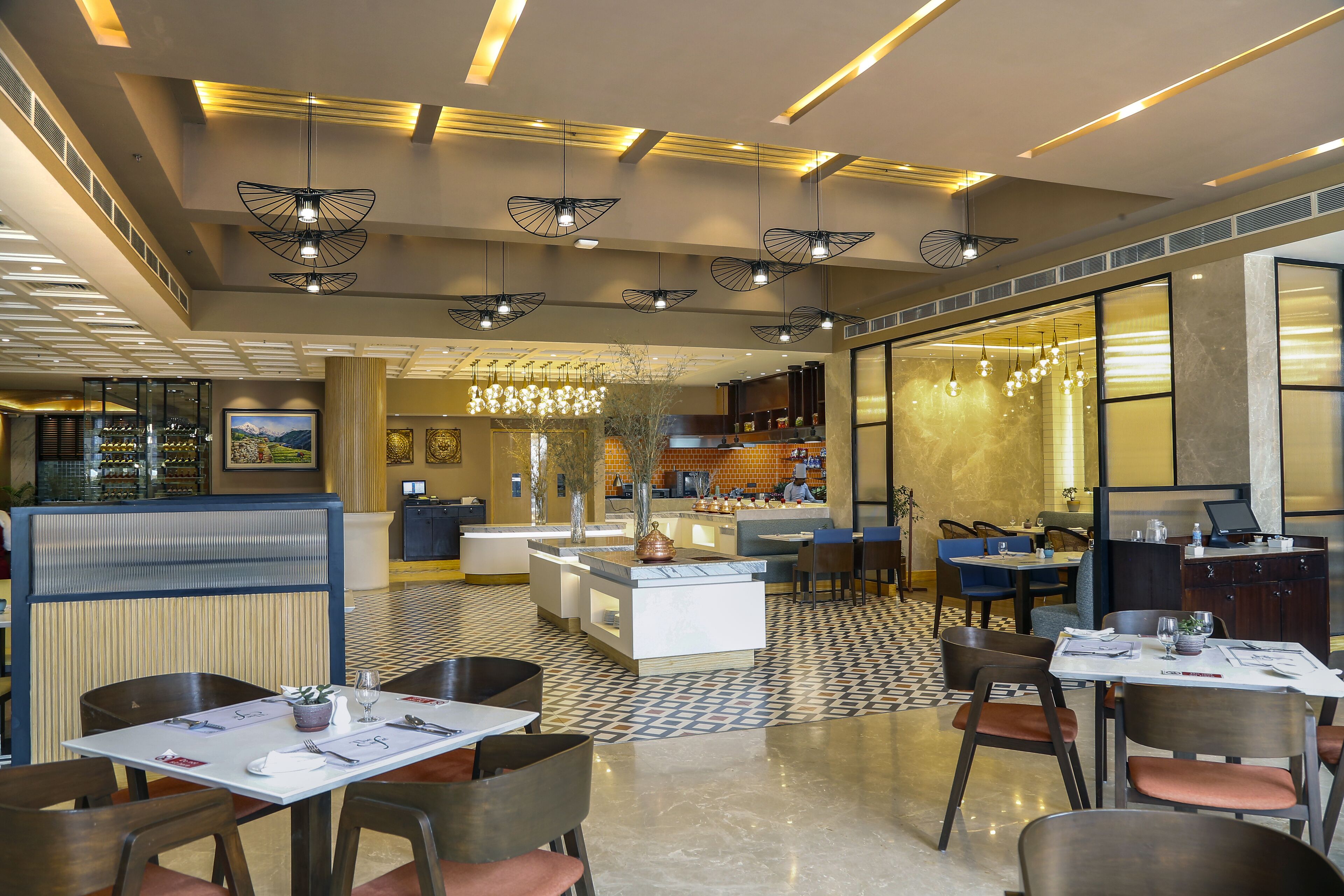 Un restaurante moderno con una isla central, varias áreas de estar y un patrón de suelo a cuadros.