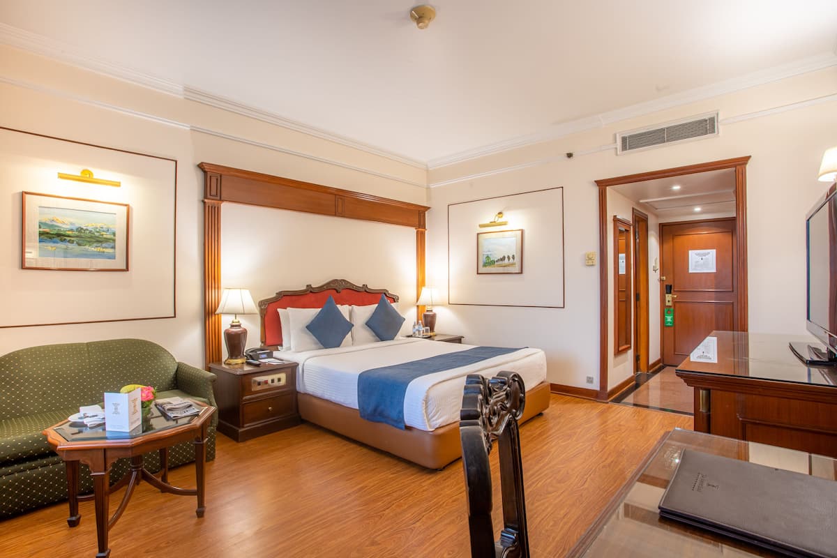 Een hotelkamer met een bed, een bureau, een stoel, een nachtkastje en een lamp.
