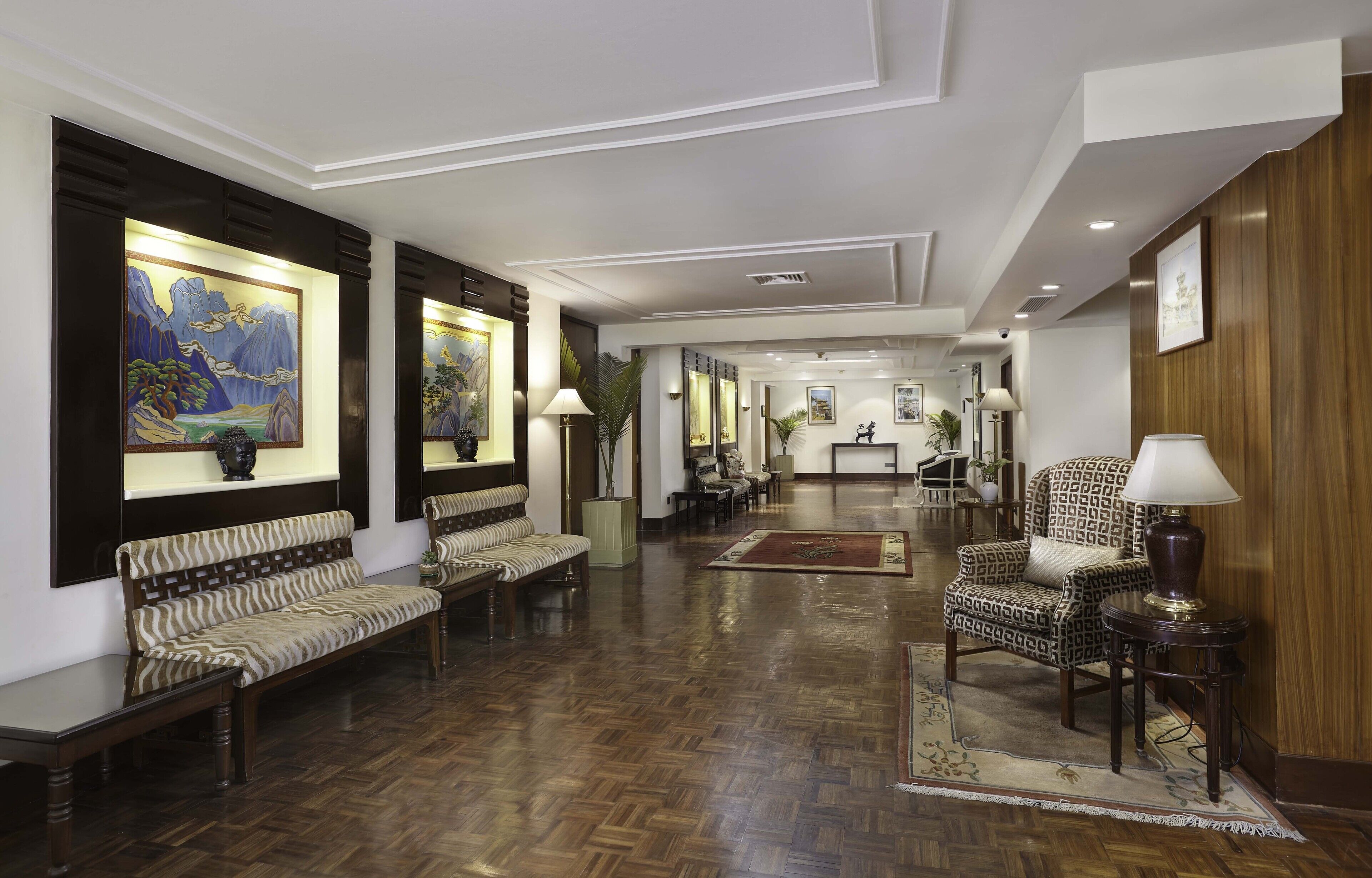 A spacious lobby with a wooden floor, seating areas, and artwork on the walls.