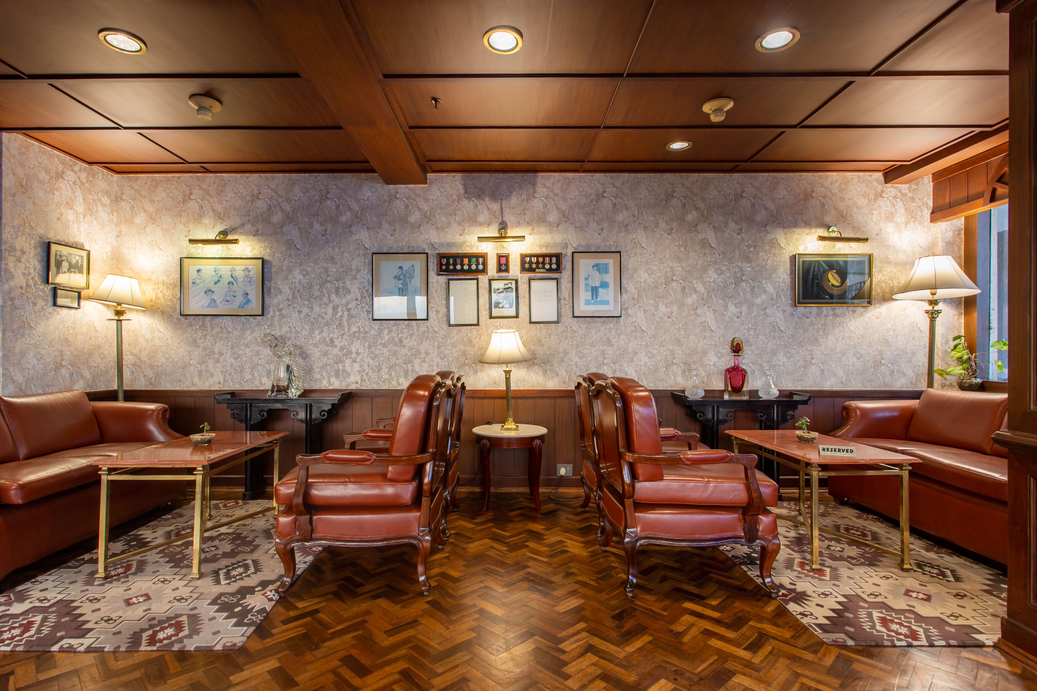 Une pièce dotée d’un parquet en bois à motifs chevrons, de canapés en cuir et d’une table centrale entourée de chaises.
