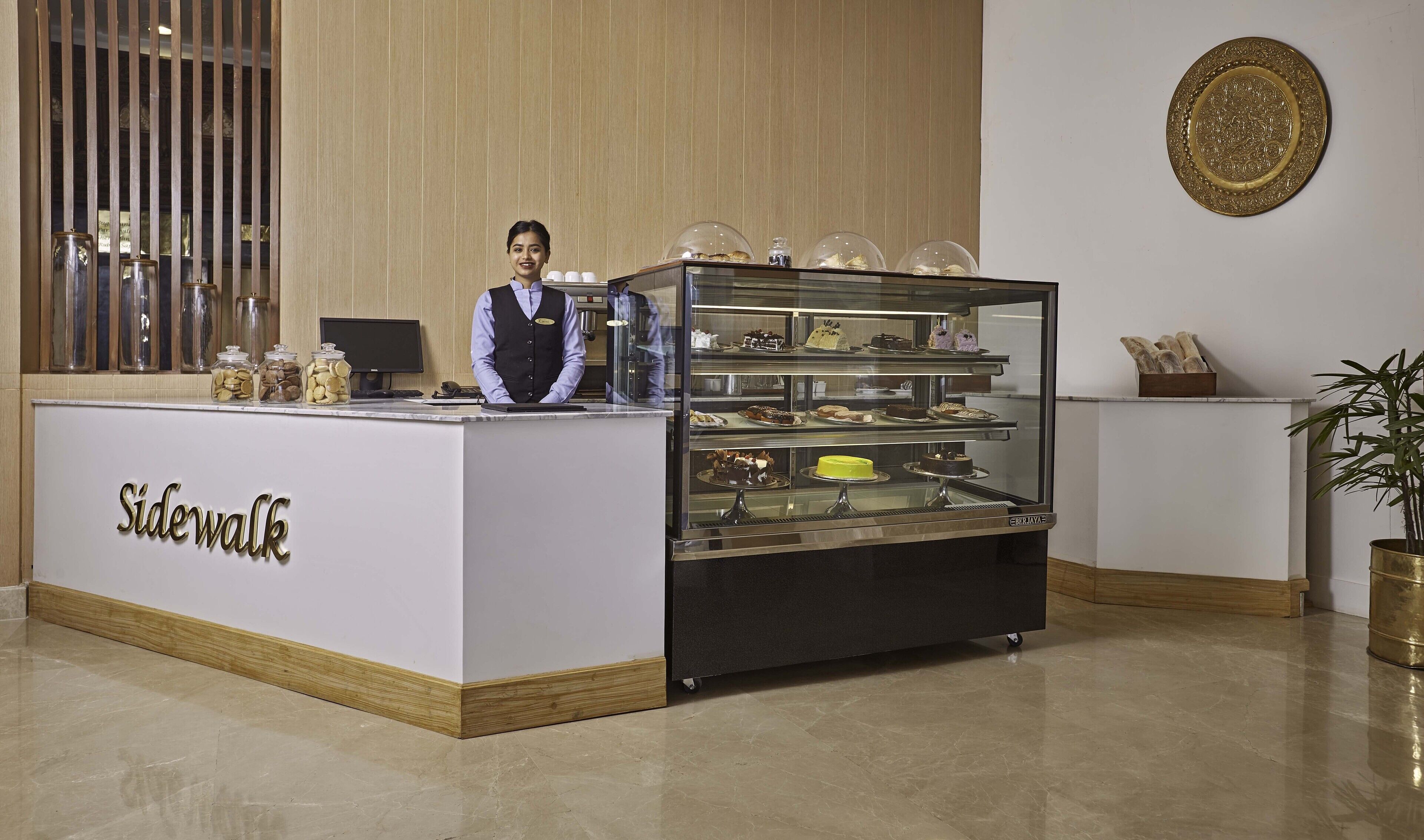 A reception desk with a glass display case of pastries and a sign that reads "Sidewalk."