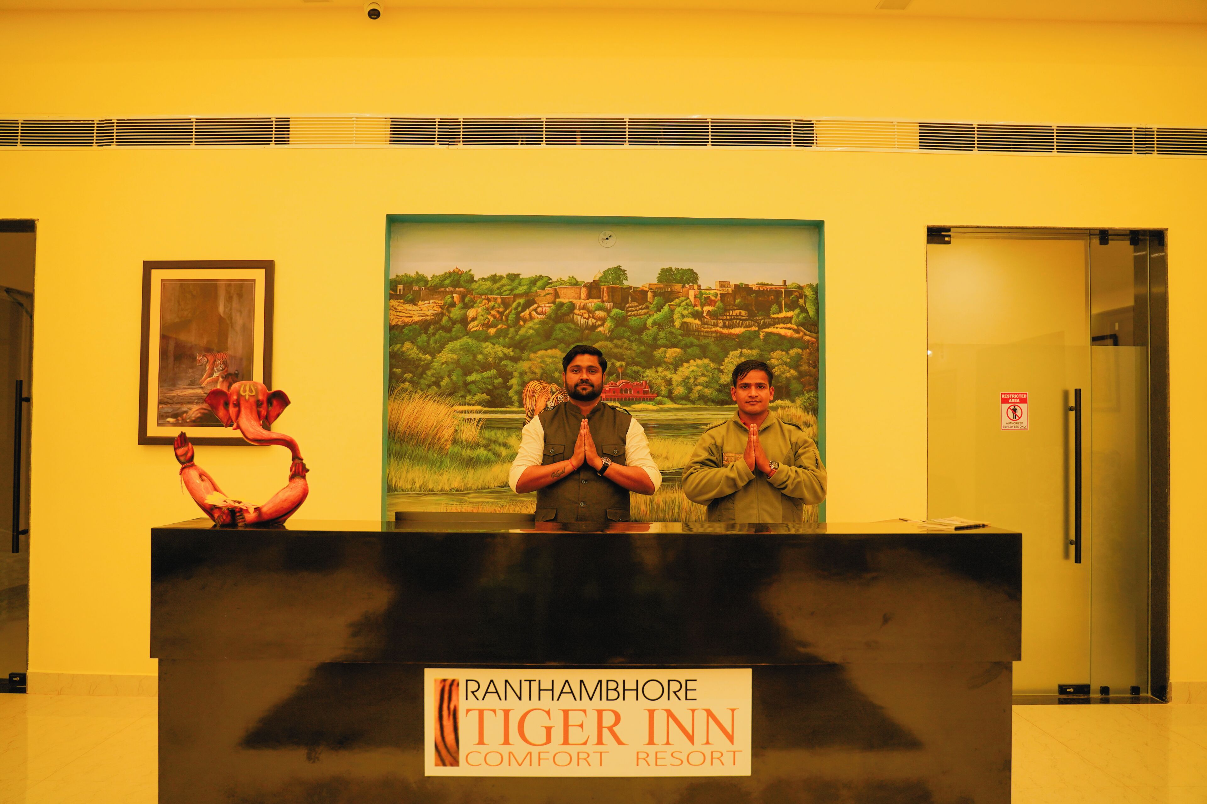 Balcão de recepção no Ranthambhore Tiger Inn Comfort Resort, com um quadro emoldurado e uma escultura na parede.