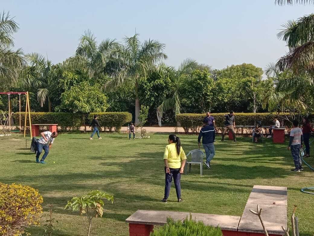 A park with a playground, benches, and people walking.